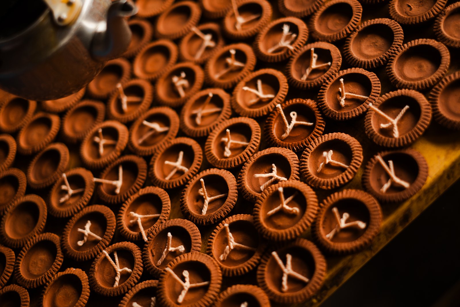 Clay cups holding wax wicks, arranged in a warm pattern