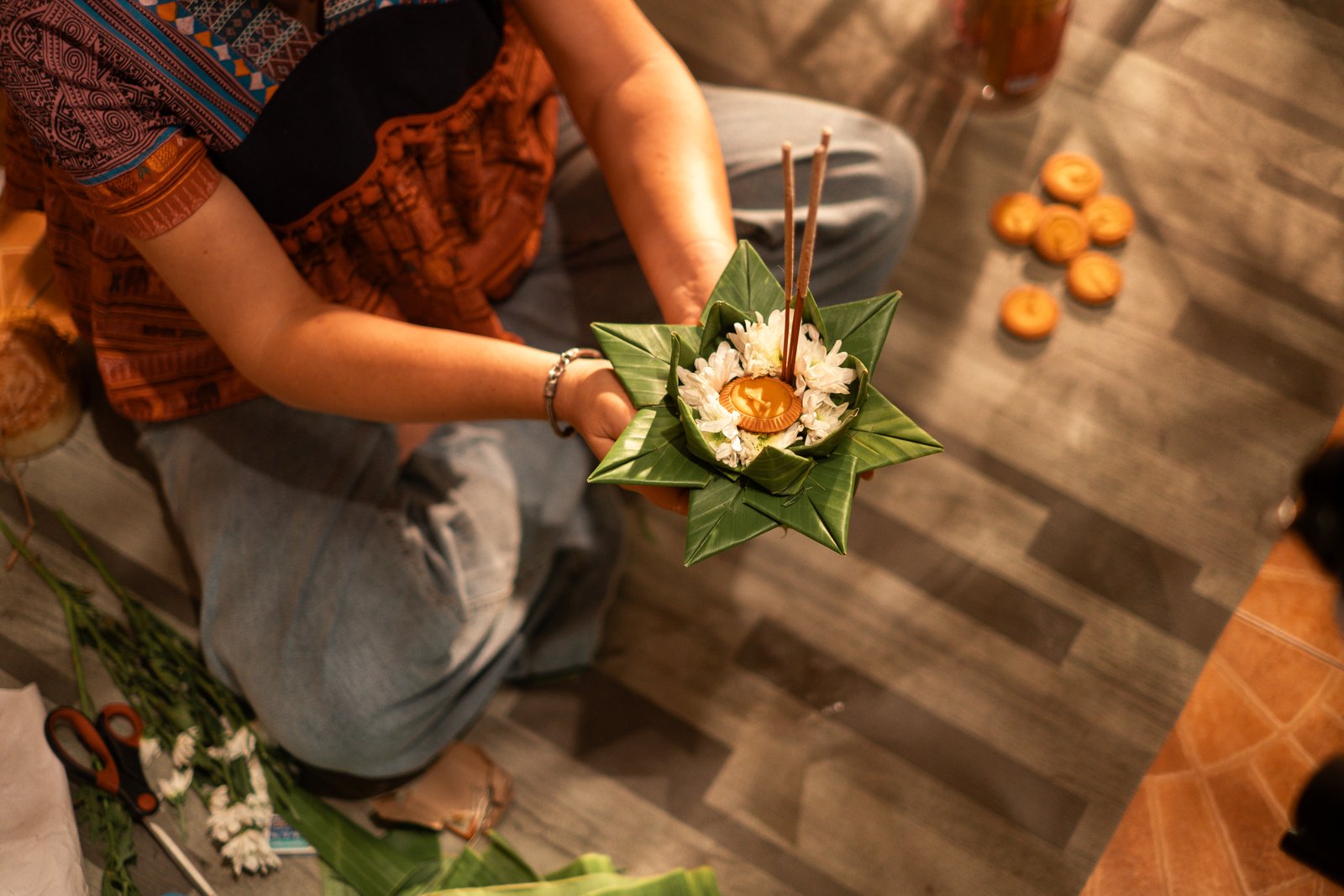 A krathong of banana leaf and flowers with lit candles, seen from above