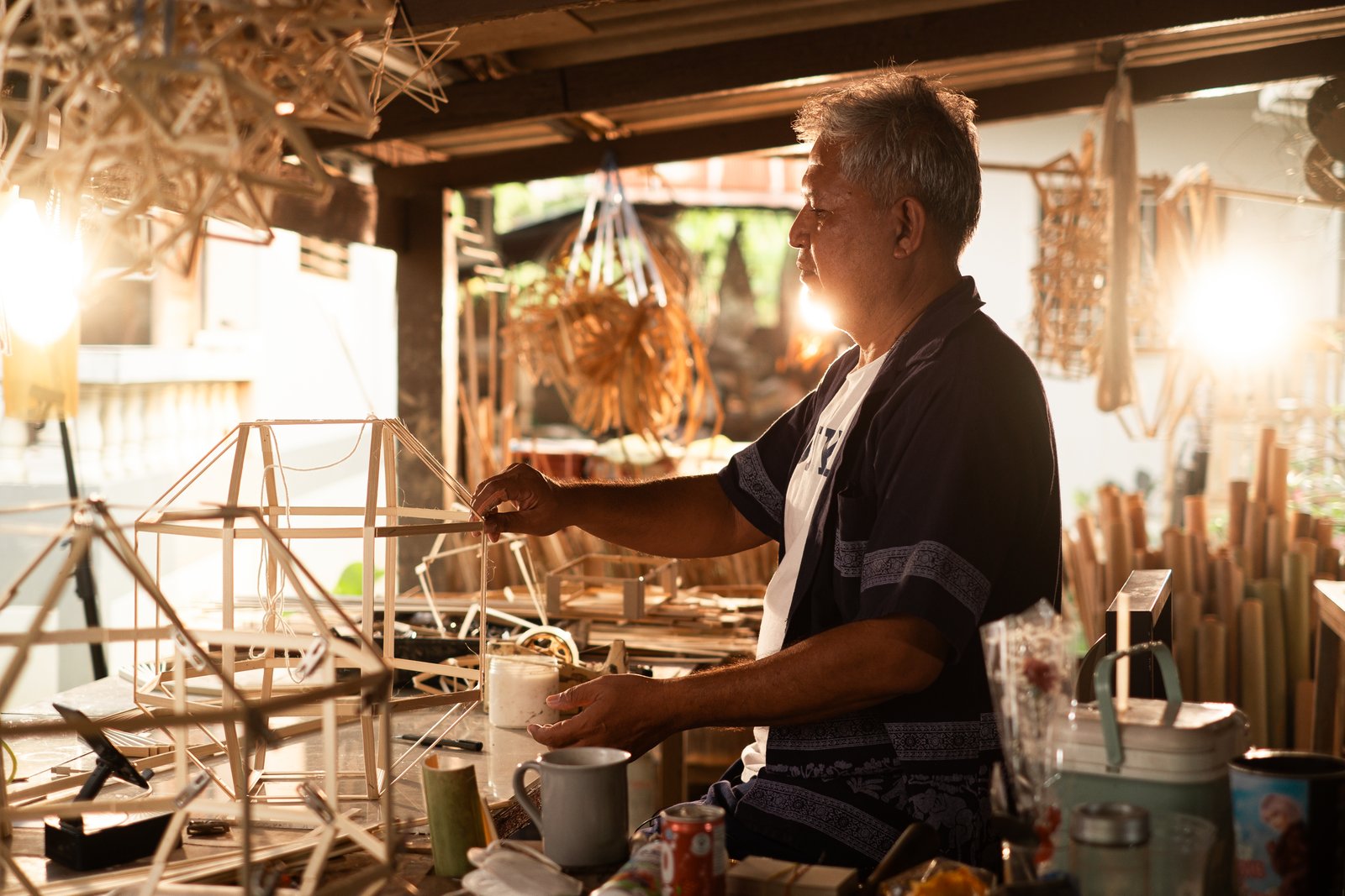 An elder craftsman standing in his bamboo workshop
