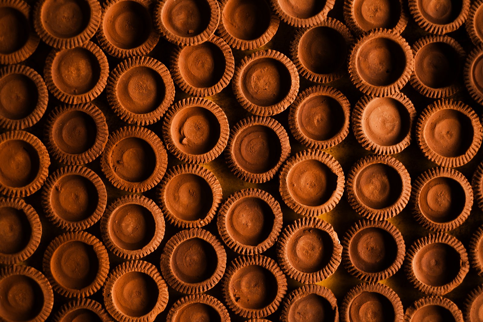 An overhead pattern of terracotta clay wax cups