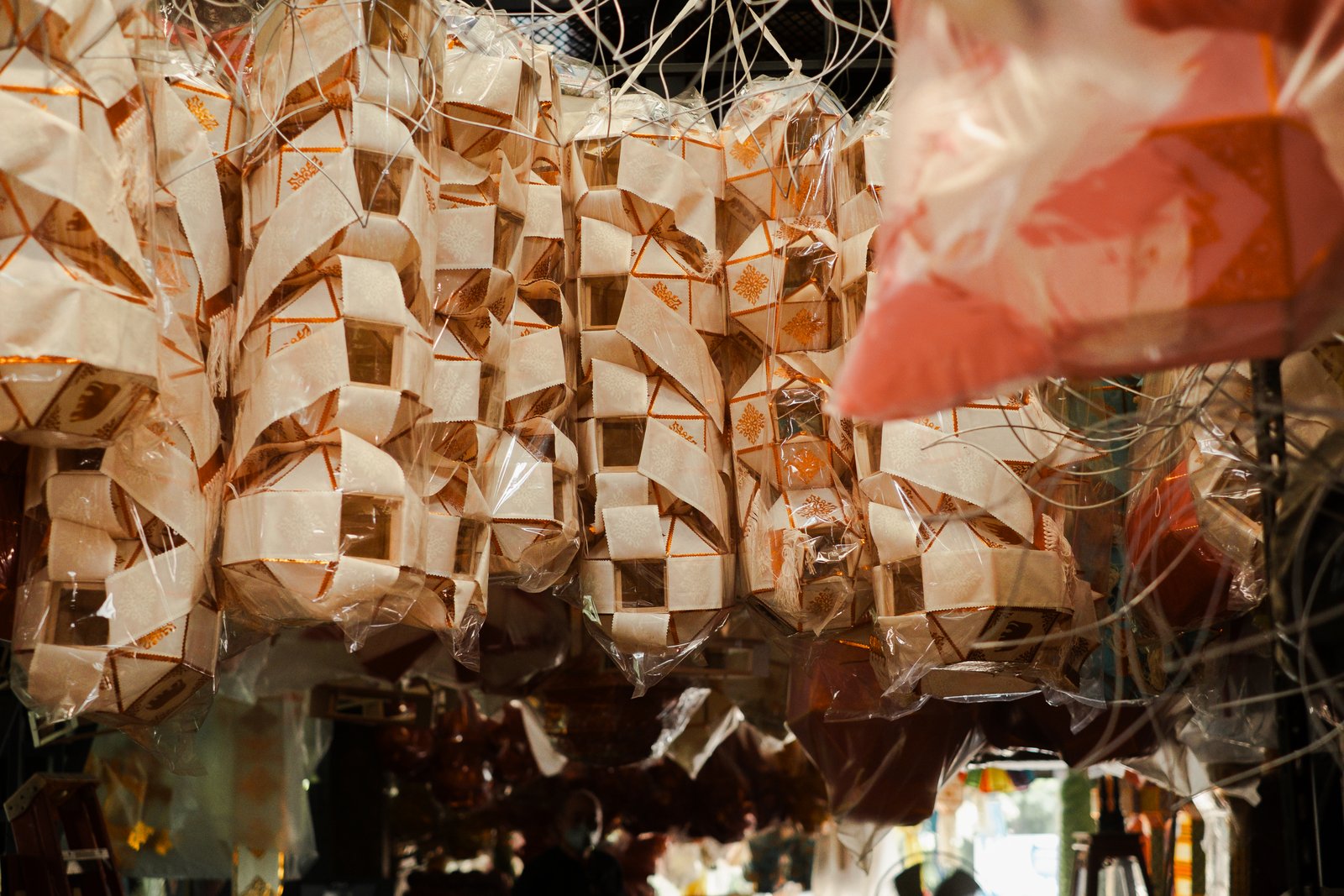 Rows of finished white paper lanterns hanging in the workshop