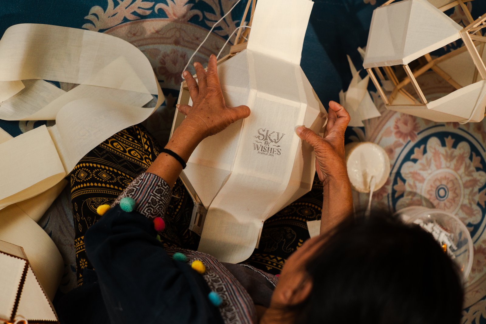 Hands pressing a stamp onto a white paper lantern, seen from above