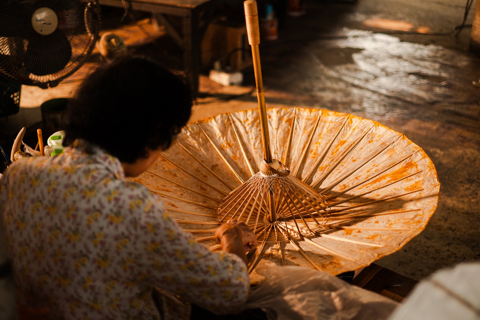A backlit bamboo umbrella frame, its maker silhouetted