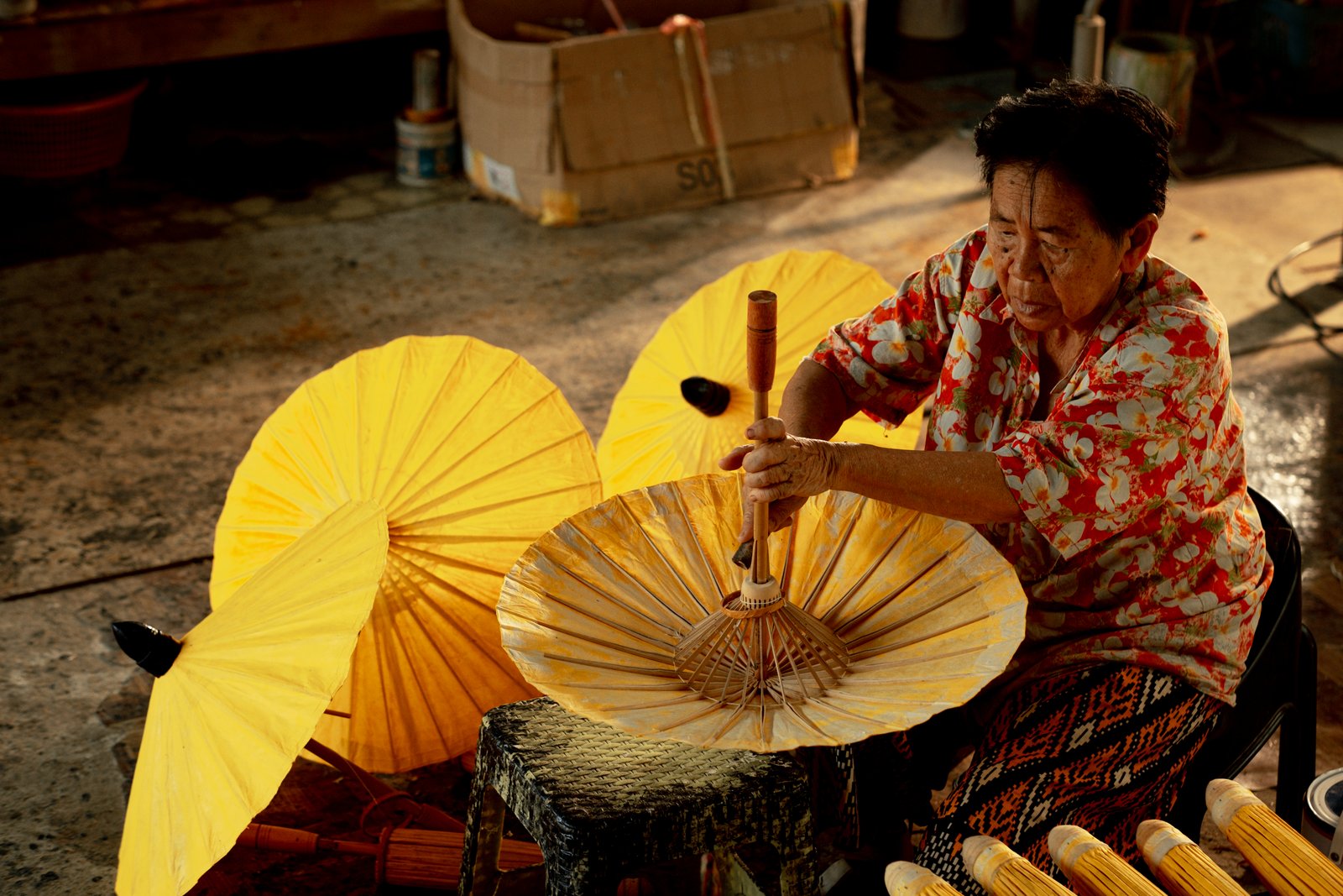 A maker shaping a yellow parasol at a bench