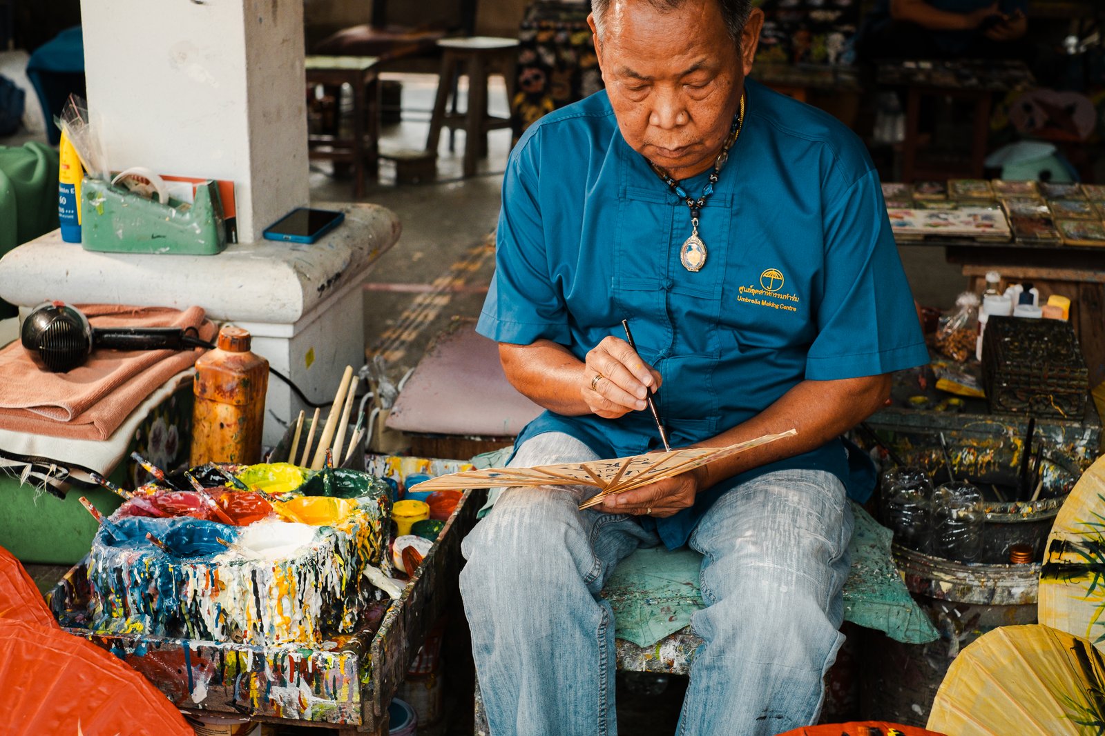 An artisan hand-painting a Sky of Wishes paper fan
